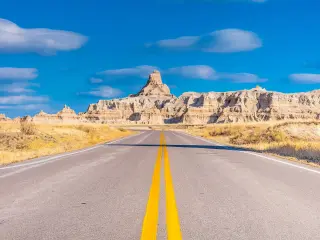 Road leading to Badlands National Park, sunny day with blue skies
