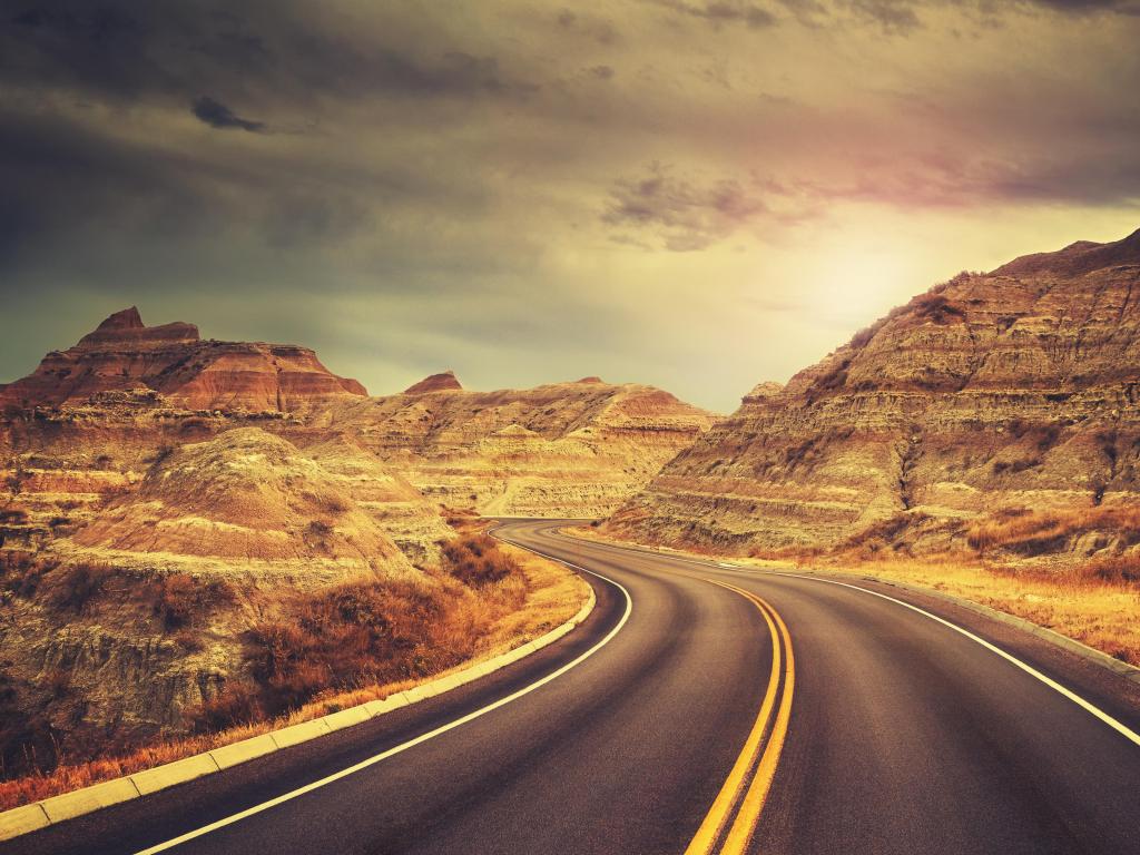 Road winding through the barren terracotta colored mountains of Badlands National Park, South Dakota at dusk