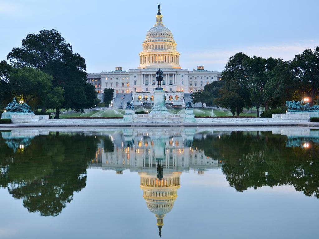 Washington DC, USA taken at US Capitol Building in a cloudy sunrise with mirror reflection in the water in the foreground. 