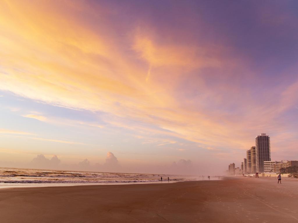 Gold and pink sunset light on a misty beach with high rise buildings