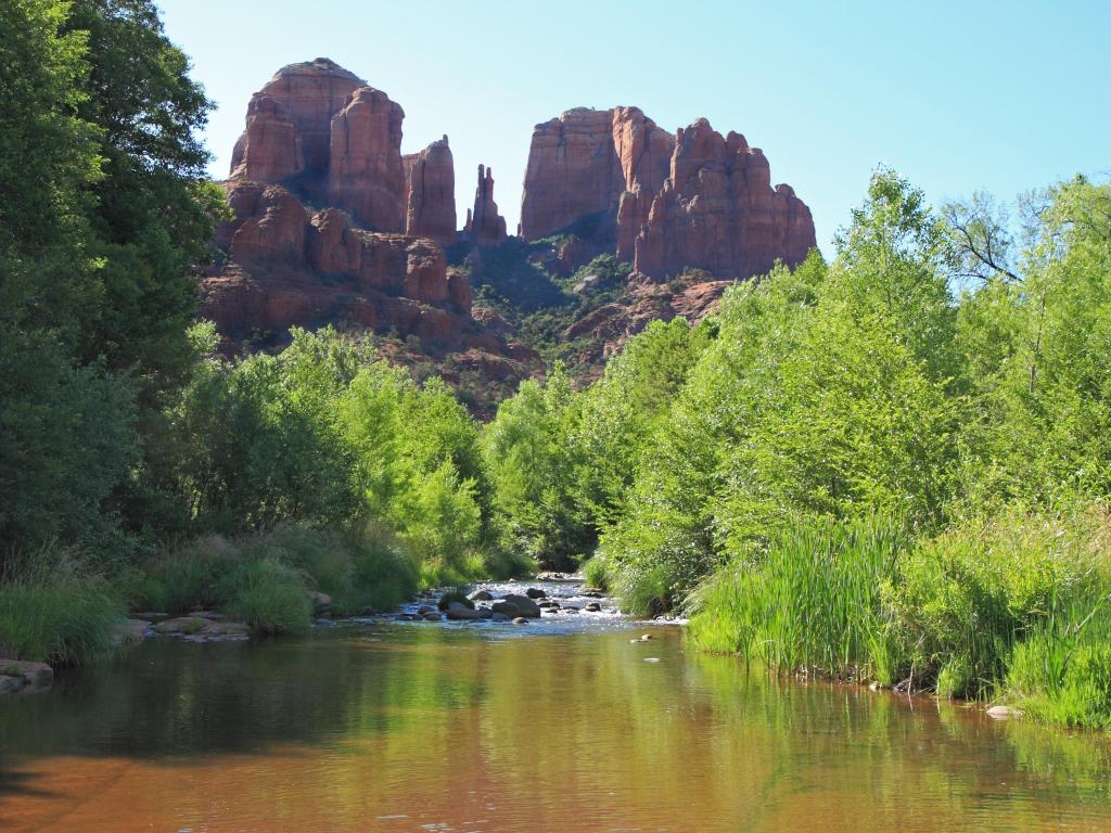 Coconino National Forest, Arizona, USA taken Cathedral Rock at sunrise with a lake in the foreground and trees surrounding it. 