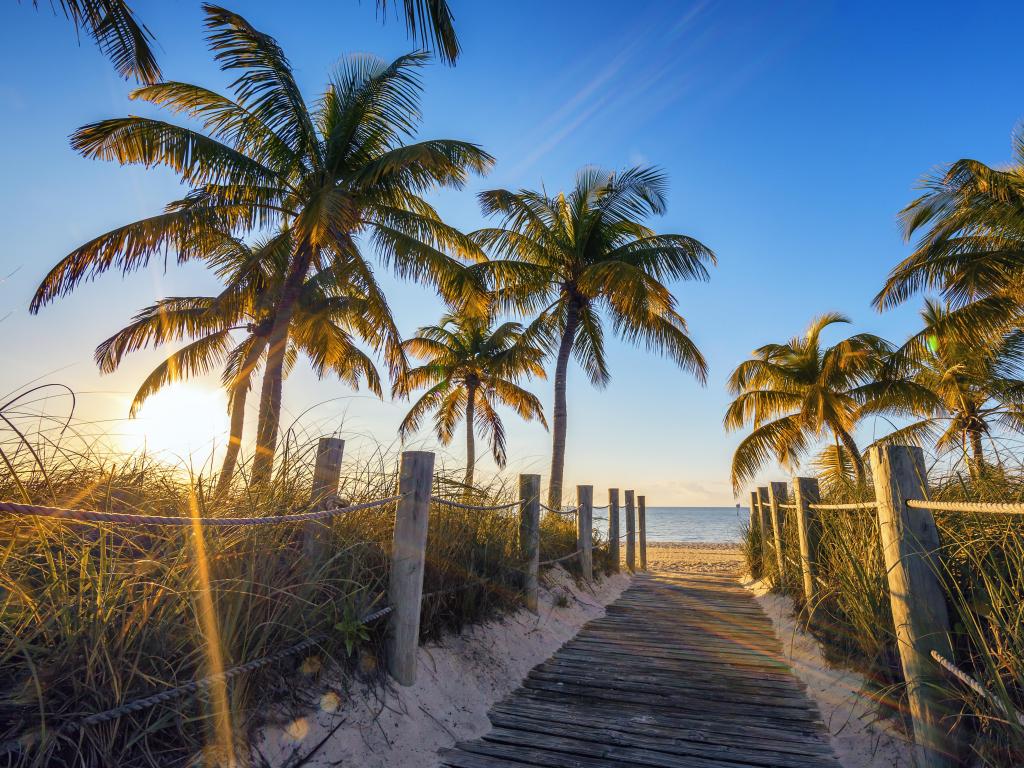 Famous passage to the beach - Key West, Florida, USA on a sunny day with palm trees in the foreground.