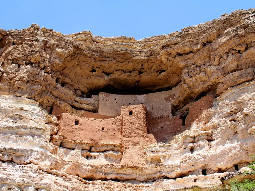  A well preserved Hopi native American cliff dwelling in a mountainside made of stone and dirt framed by the green leaves found in Montezuma Castle National Monument, Arizona