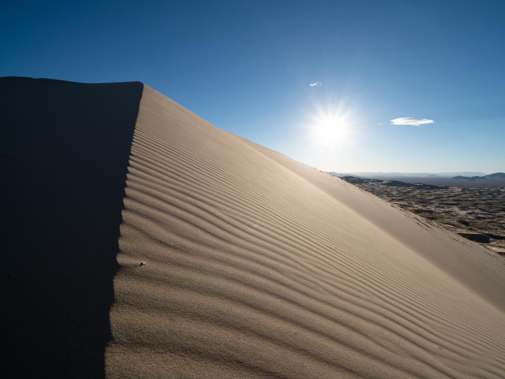 Massive sand dune with sun shining from behind