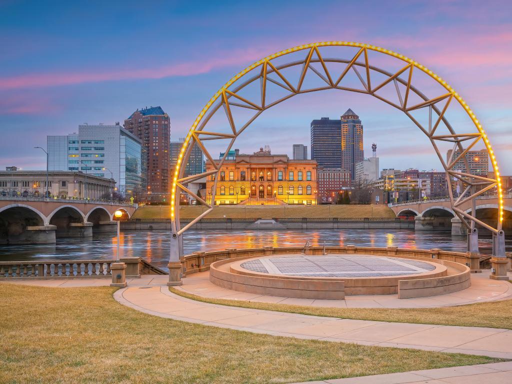 Downtown Des Moines Iowa city skyline at sunset with a sculpture in the foreground and the river behind