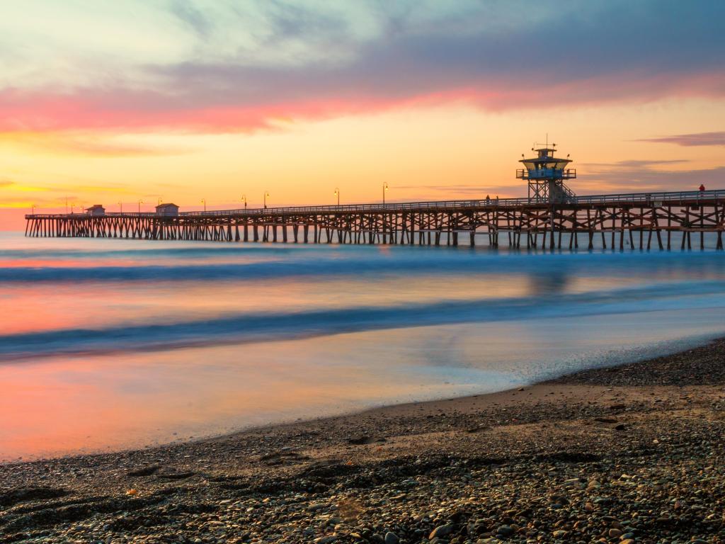 San Clemente Pier at sunset with a pebble beach in the foreground