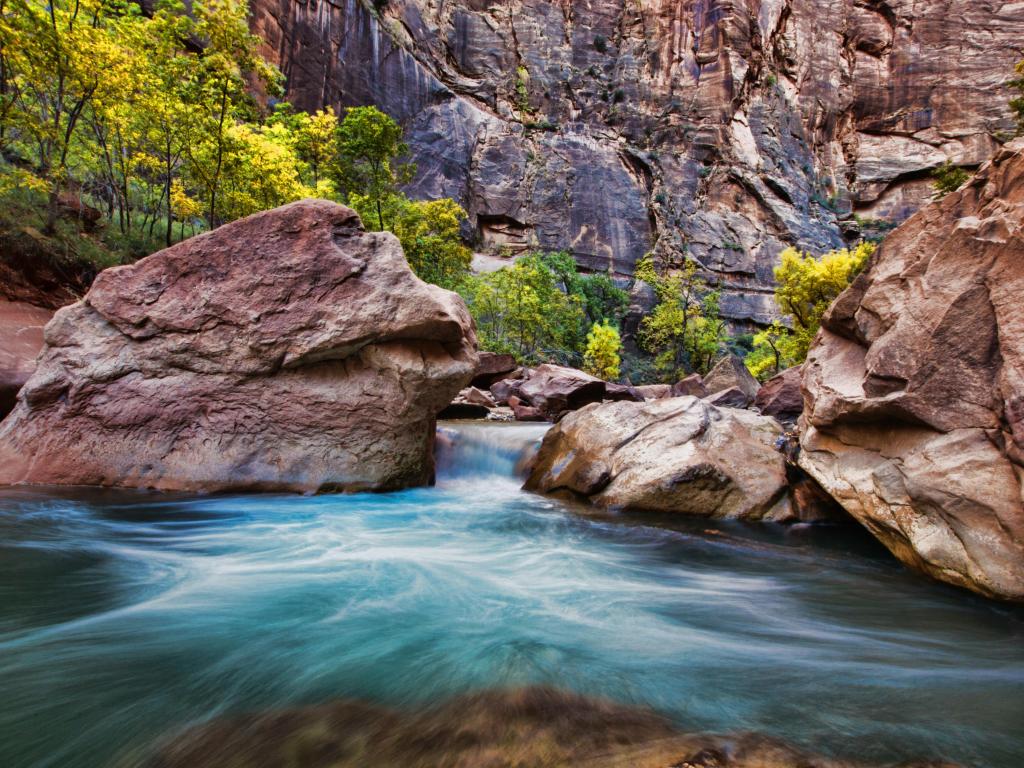 Virgin Narrows River in Zion National Park. The photo depicts a fast flowing river in a red canyon.