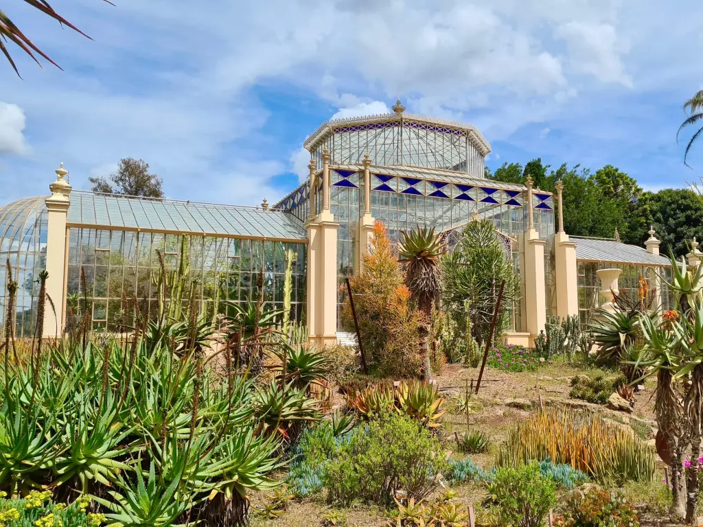 A stunning, historic stained glass greenhouse located in the Adelaide Botanic Garden on a sunny day