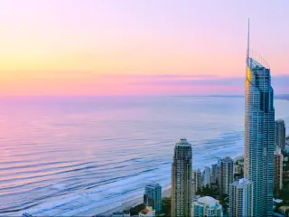 Sunrise casts a pink light over a long stretch of coast with highrise buildings